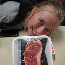 Headshot of Chelsie Dahlgren with a new york strip steak